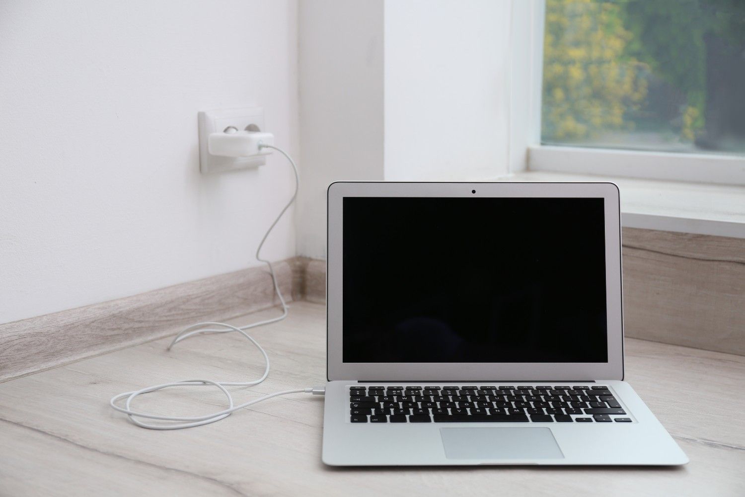 modern-laptop-with-charger-floor-near-white-wall (1).jpg